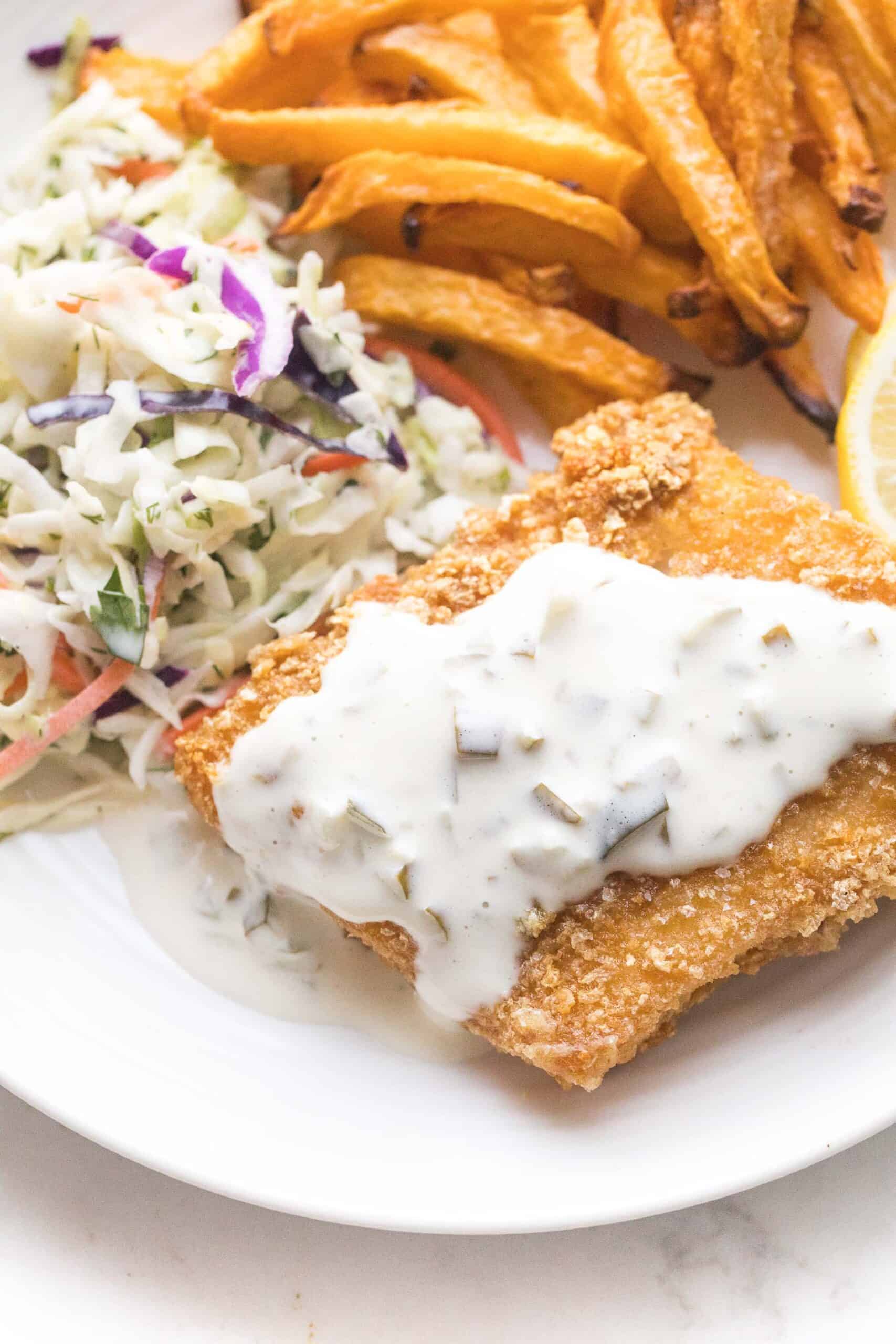 fish + chips with coleslaw + tartar sauce on a white plate