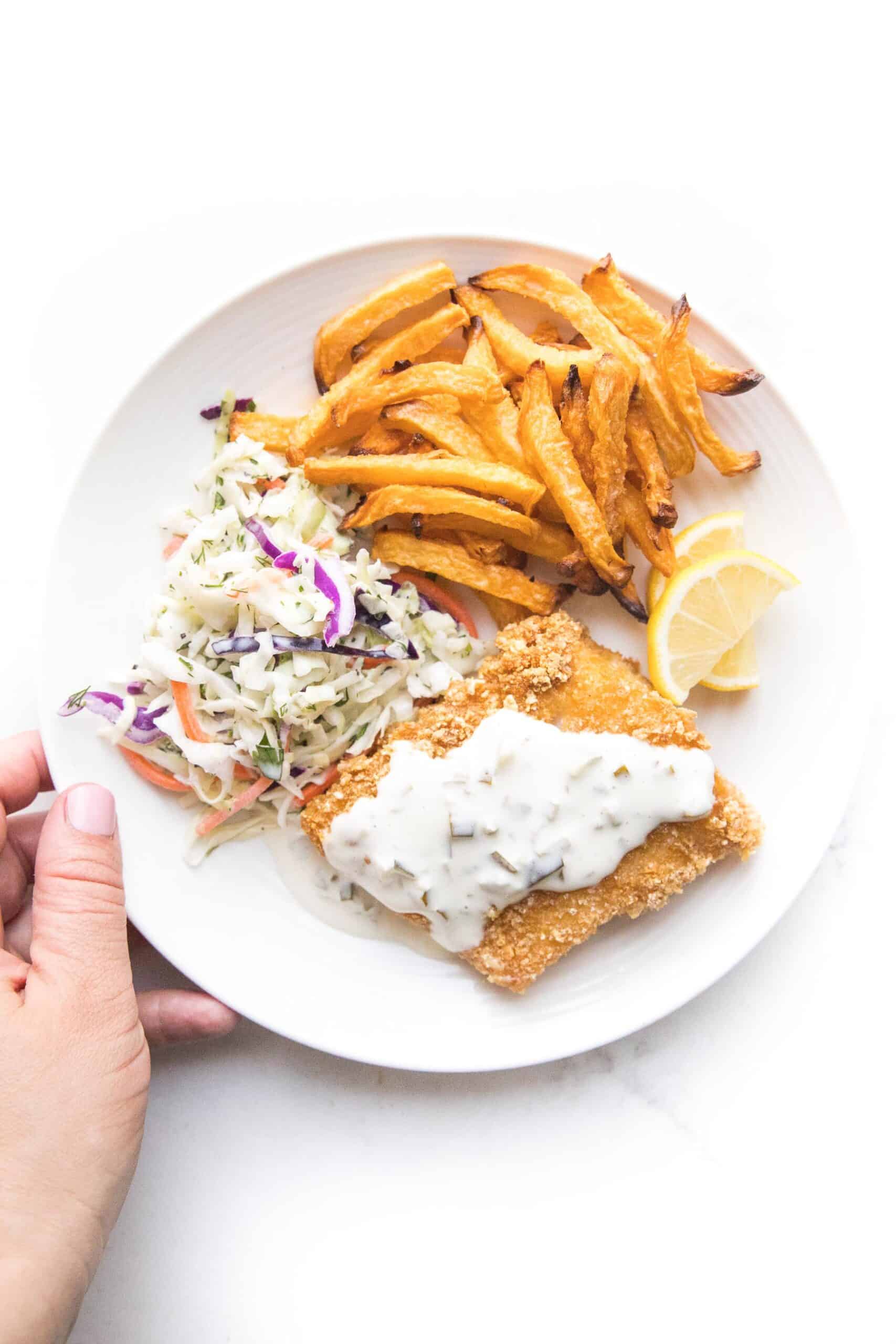 fish + chips with coleslaw + tartar sauce on a white plate