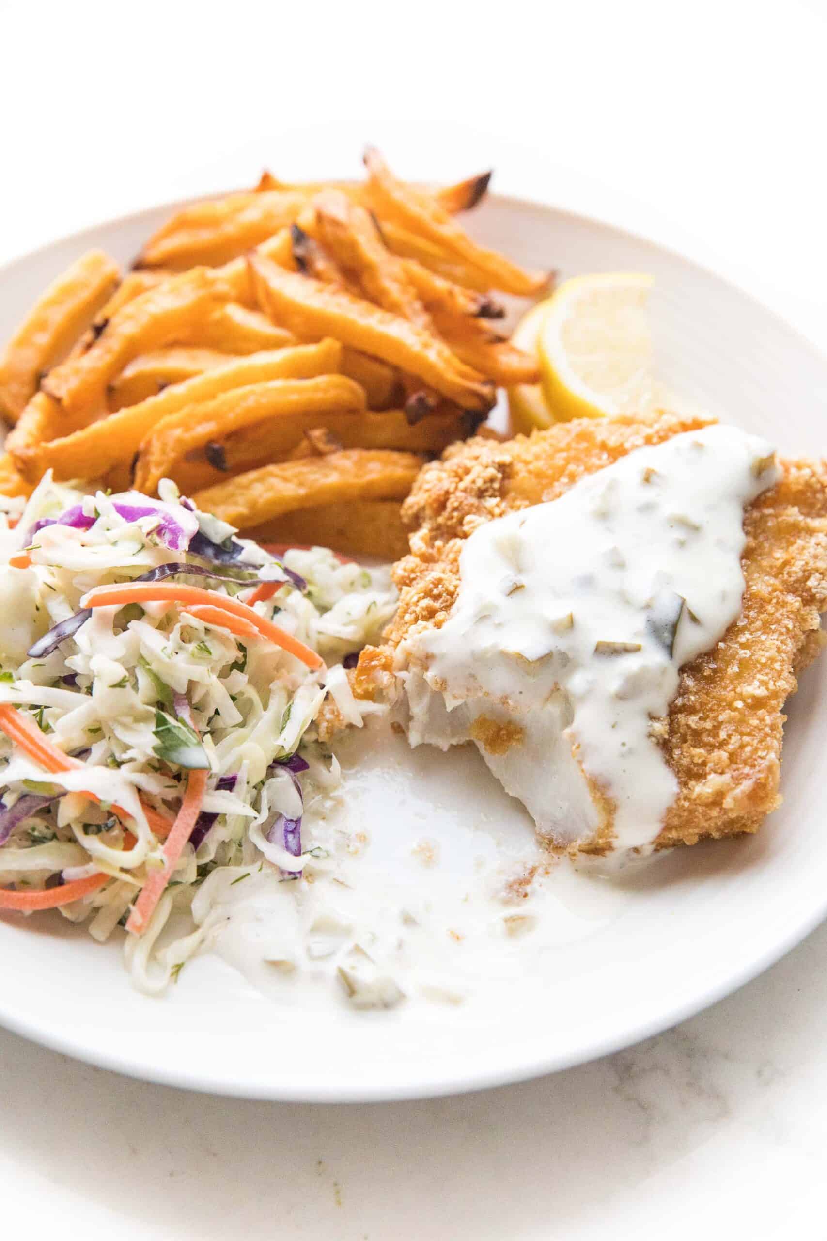 fish + chips with coleslaw + tartar sauce on a white plate