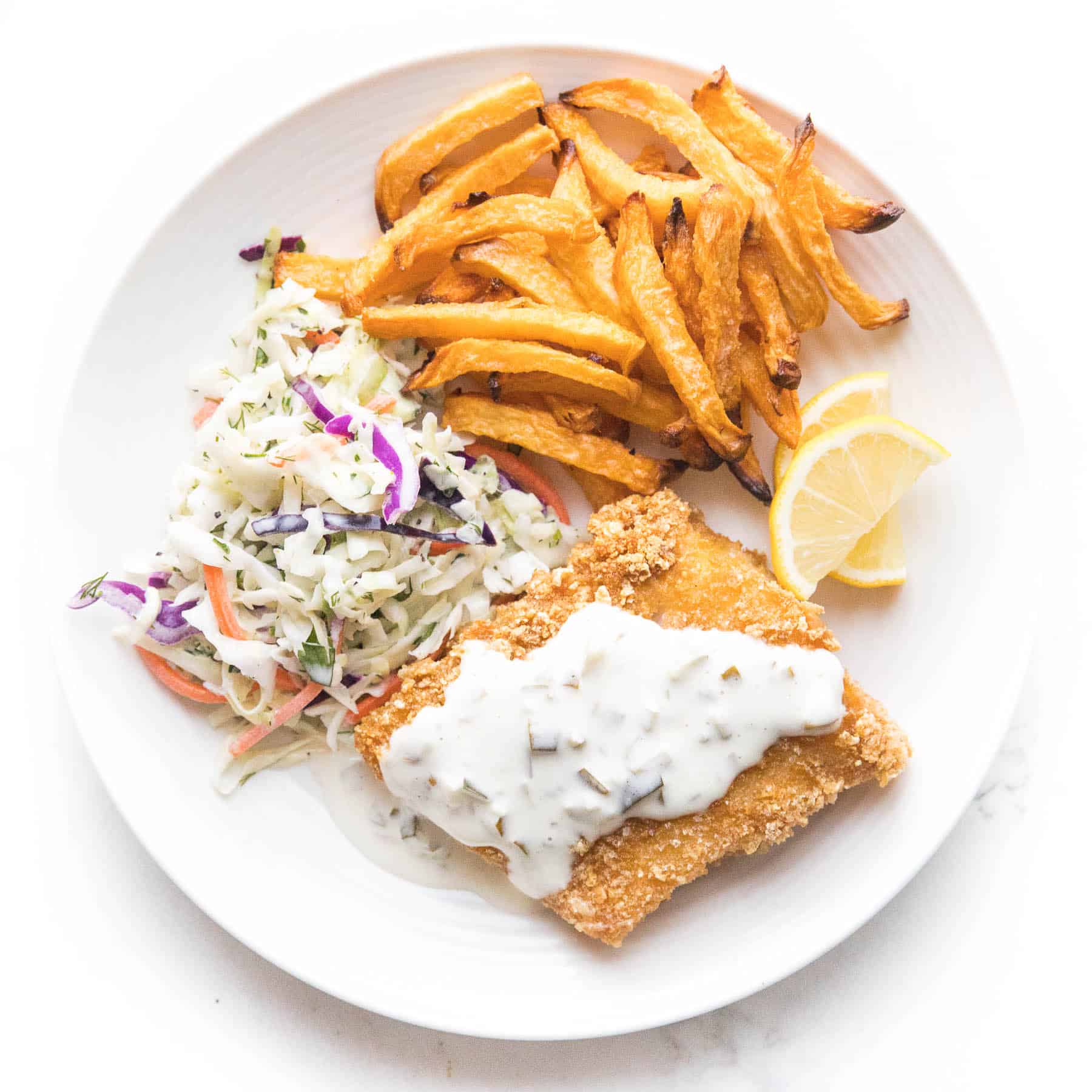 fish + chips with coleslaw + tartar sauce on a white plate