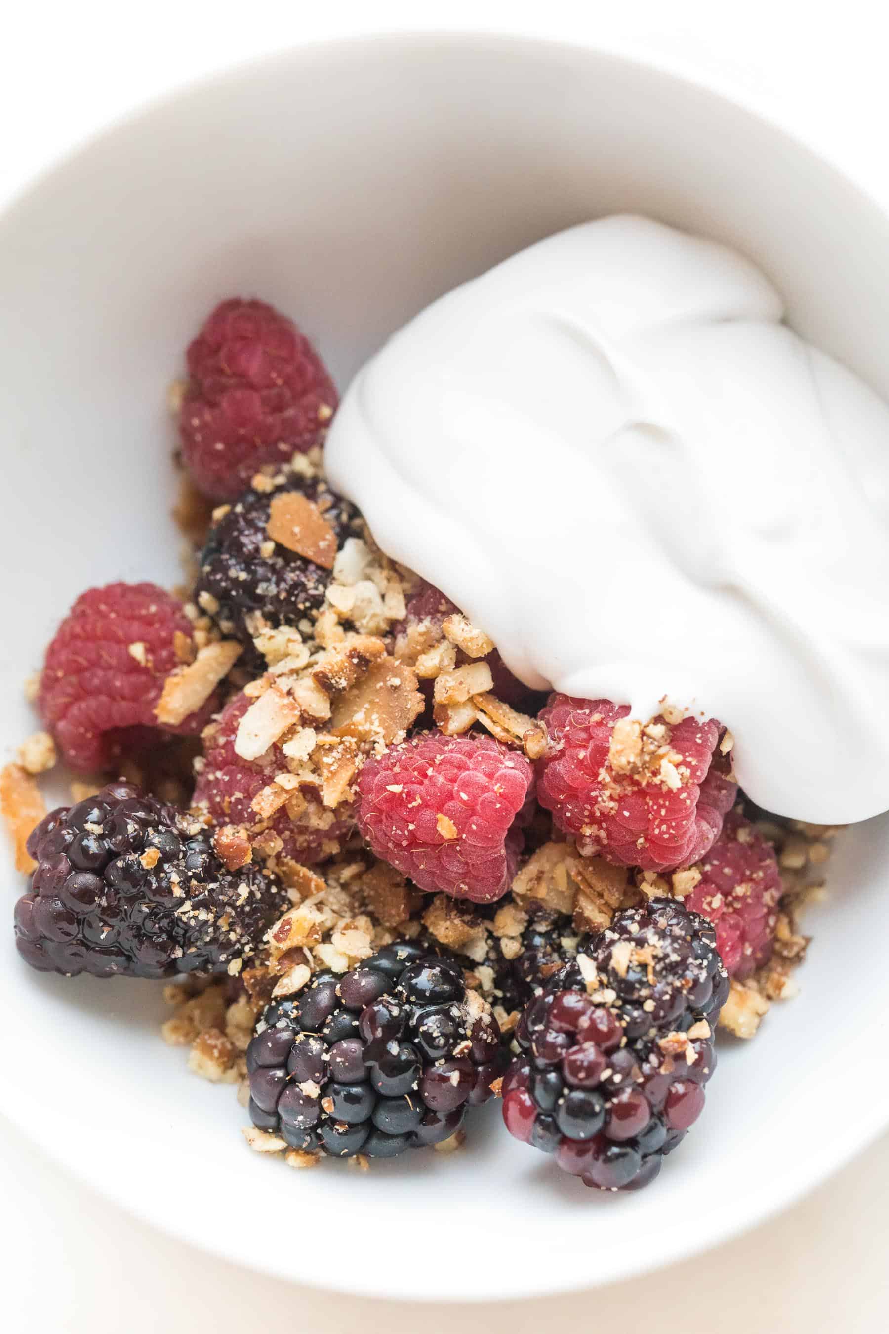 whole30 + keto raw berry crisp: raspberries + blackberries topped with pecan + shredded coconut with coconut whipped cream