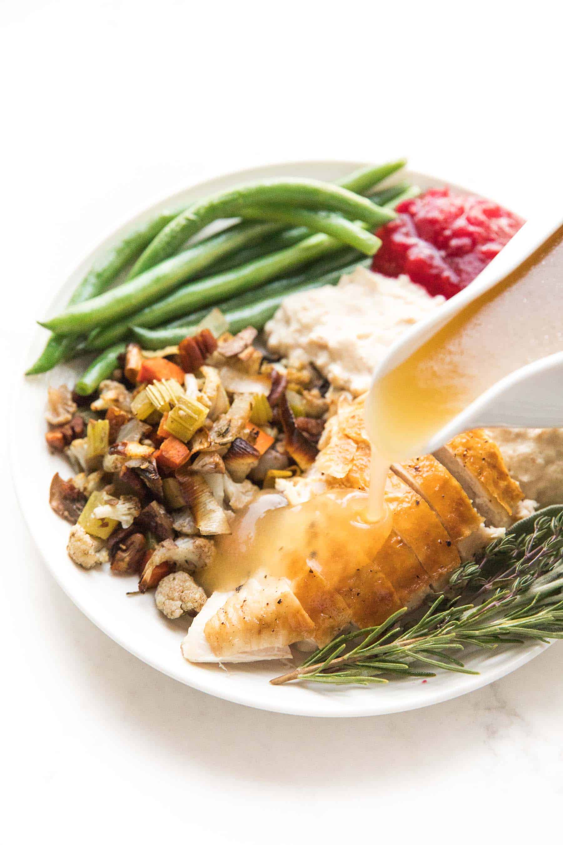 keto stuffing made with fresh herbs, chicken broth, roasted vegetables, pecans, cauliflower, and olive oil on a thanksgiving plate with other low carb mains and sides.