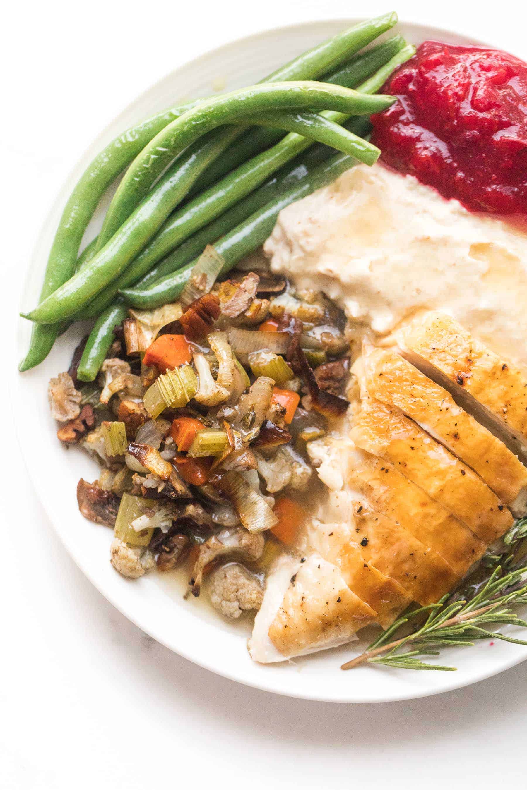 keto thanksgiving dinner plate with turkey, cauliflower stuffing, green beans, mashed cauliflower, and keto cranberry sauce