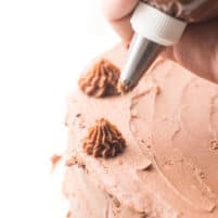 Piping chocolate frosting onto a cake