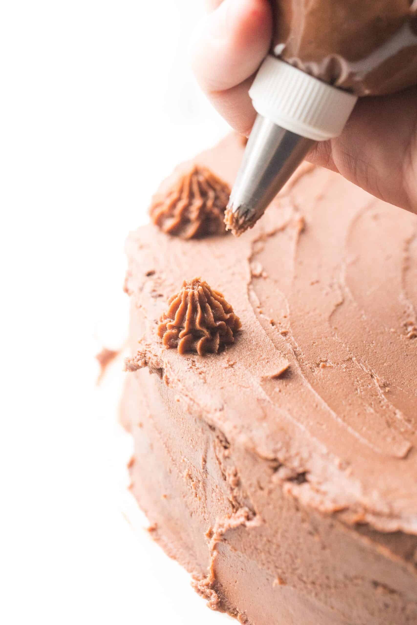 Piping chocolate frosting onto a cake