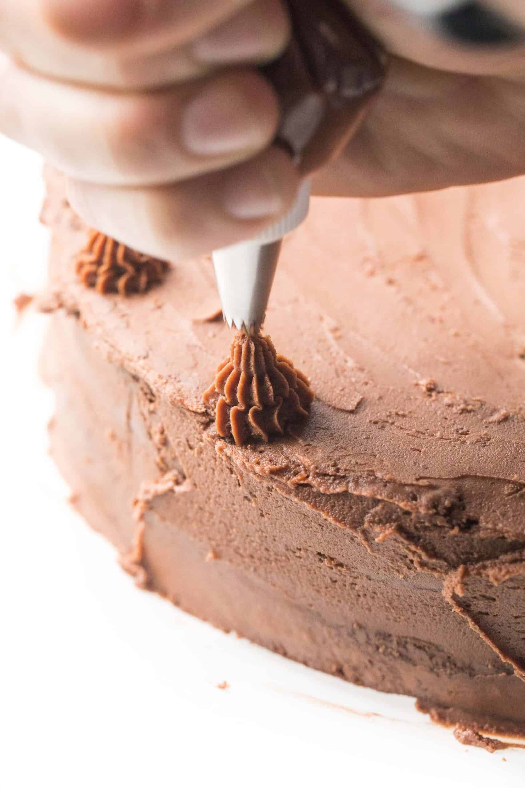 Piping chocolate frosting onto a cake